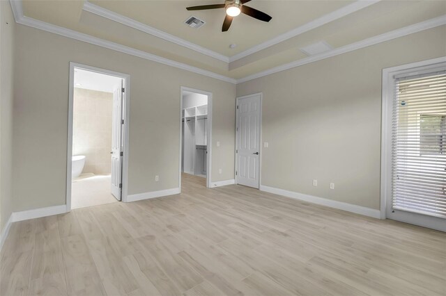 13303 Swiftwater Way, Lakewood Ranch, FL 34211 - unfurnished bedroom featuring a tray ceiling, ornamental molding, light wood-style flooring, baseboards, and a walk in closet