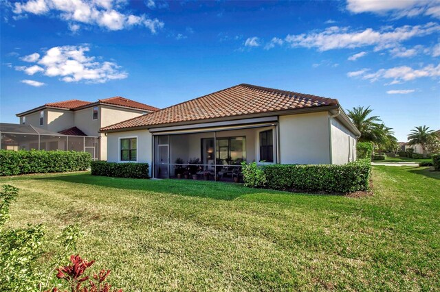 13303 Swiftwater Way, Lakewood Ranch, FL 34211 - back of house featuring a tile roof, stucco siding, a sunroom, and a yard