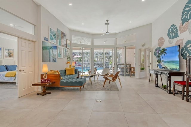 living area featuring a towering ceiling, light tile patterned floors, and ceiling fan