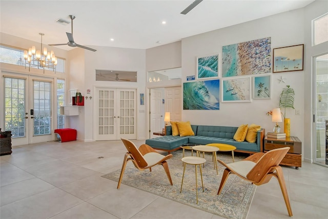 tiled living room with french doors, ceiling fan with notable chandelier, and a high ceiling