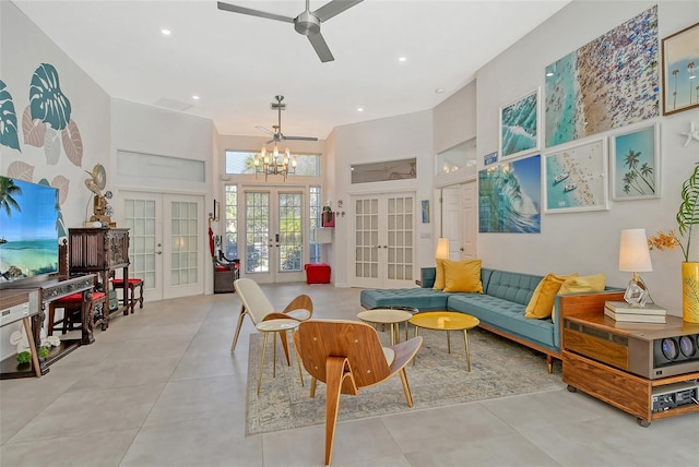 tiled living room with a high ceiling, ceiling fan with notable chandelier, and french doors