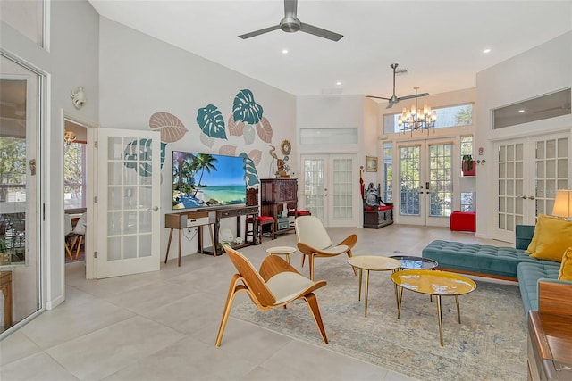 tiled living room featuring french doors, ceiling fan with notable chandelier, and a high ceiling