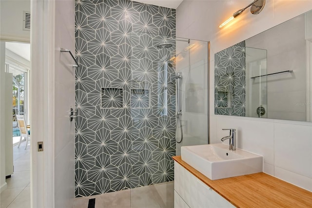 bathroom with tile walls, vanity, and tiled shower