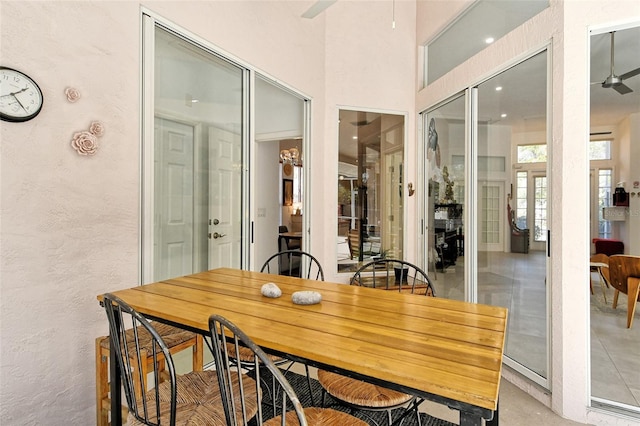 dining space with ceiling fan and a towering ceiling