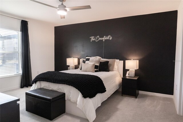 bedroom featuring an accent wall, light carpet, and baseboards