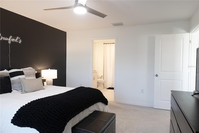 bedroom with light carpet, baseboards, visible vents, a ceiling fan, and ensuite bath