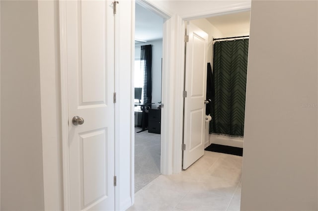 corridor featuring light colored carpet and light tile patterned flooring