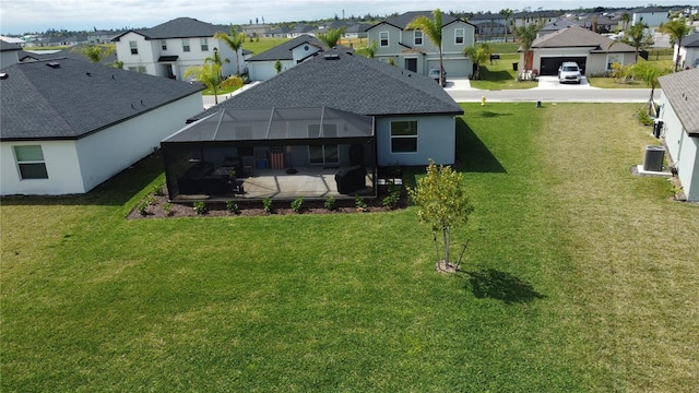 back of house with a residential view, glass enclosure, a lawn, and central AC unit