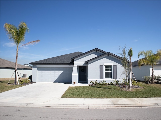 single story home with a front lawn, concrete driveway, an attached garage, and stucco siding