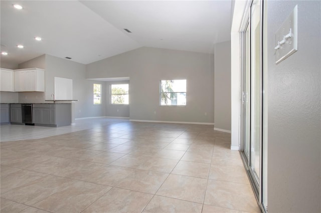 unfurnished living room featuring vaulted ceiling, sink, and light tile patterned floors