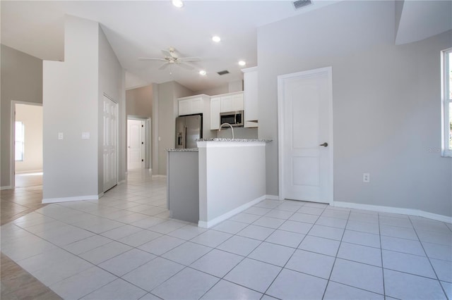 kitchen featuring ceiling fan, stainless steel appliances, light stone countertops, white cabinets, and light tile patterned flooring