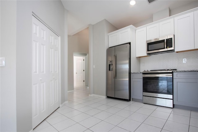 kitchen with white cabinetry, light tile patterned floors, stainless steel appliances, light stone countertops, and backsplash