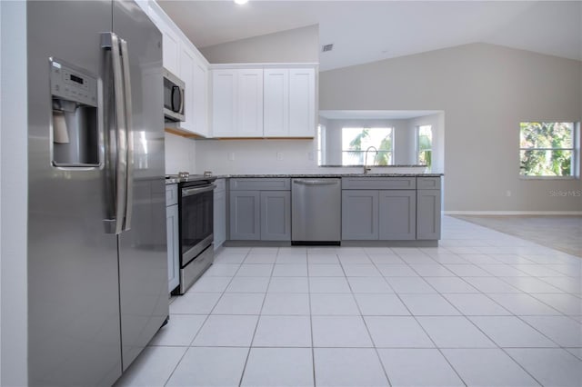 kitchen featuring gray cabinets, white cabinetry, appliances with stainless steel finishes, and vaulted ceiling