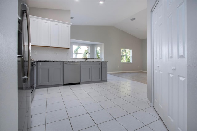 kitchen featuring lofted ceiling, gray cabinets, dishwasher, white cabinetry, and light tile patterned flooring