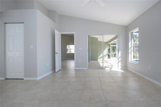 unfurnished room with a wealth of natural light, vaulted ceiling, ceiling fan, and light tile patterned flooring