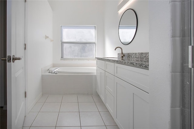 bathroom with tile patterned flooring, vanity, and tiled bath