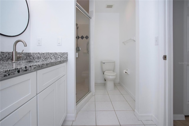 bathroom featuring tile patterned flooring, toilet, vanity, and walk in shower