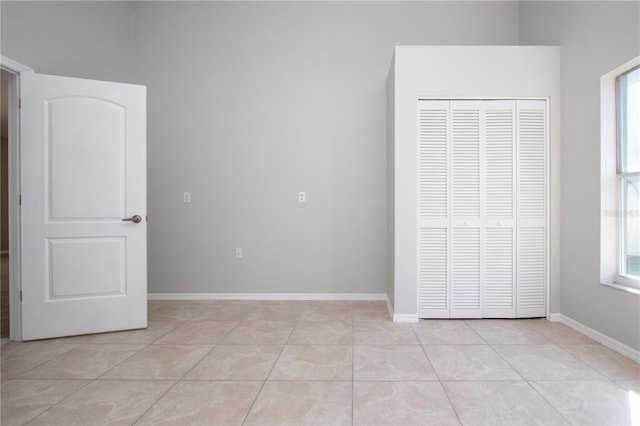 unfurnished bedroom featuring a closet, multiple windows, and light tile patterned floors