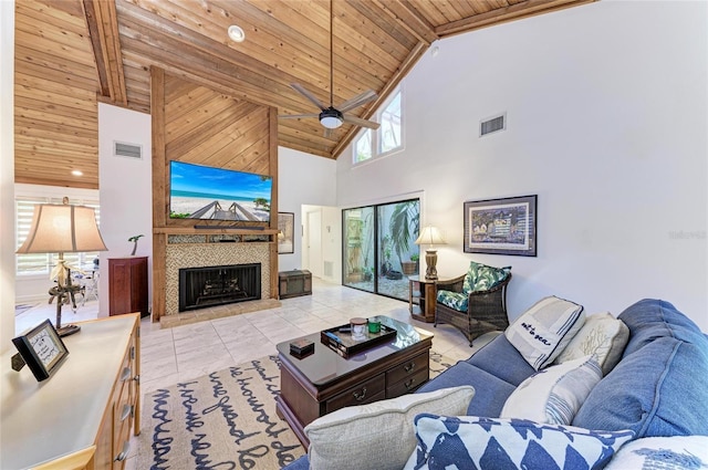 tiled living room with beamed ceiling, ceiling fan, a tiled fireplace, and wooden ceiling