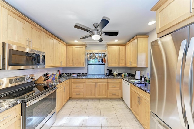 kitchen featuring appliances with stainless steel finishes, dark stone countertops, and light brown cabinetry