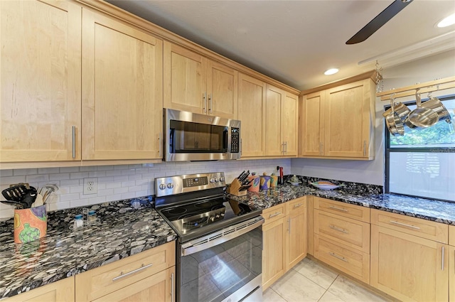 kitchen featuring appliances with stainless steel finishes, light brown cabinets, and dark stone counters