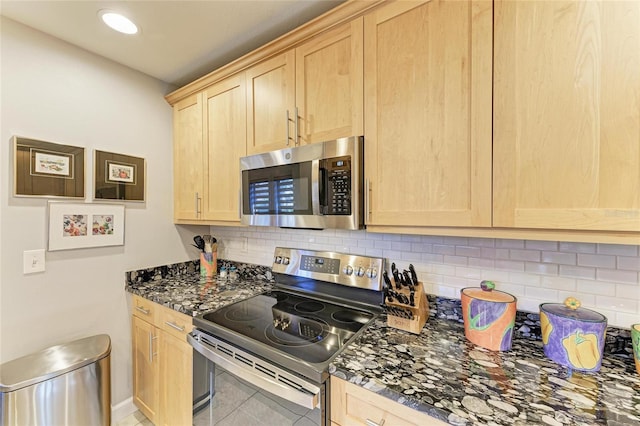 kitchen featuring appliances with stainless steel finishes, dark stone countertops, light brown cabinetry, decorative backsplash, and tile patterned floors