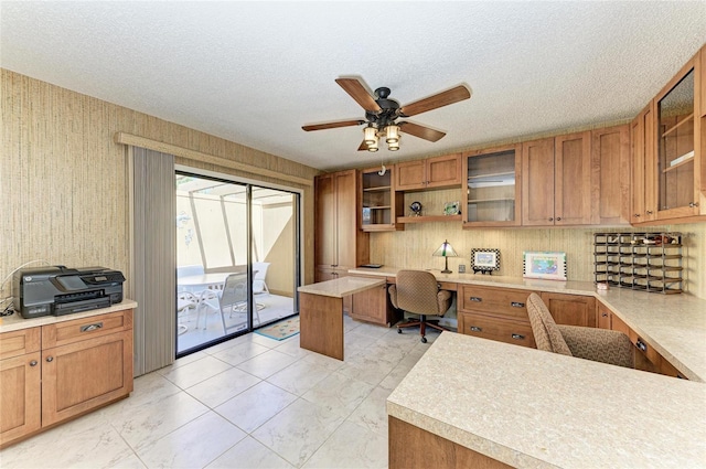 office space featuring ceiling fan, built in desk, and a textured ceiling