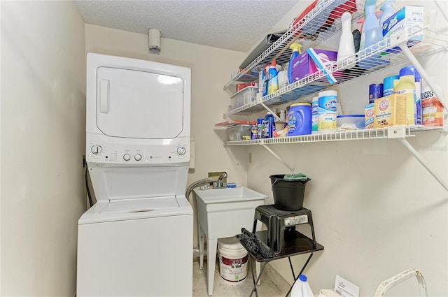 laundry area with stacked washer / drying machine and a textured ceiling