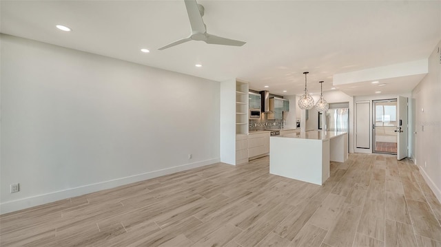 kitchen with open floor plan, light countertops, hanging light fixtures, light wood-type flooring, and a center island