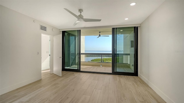 spare room featuring visible vents, floor to ceiling windows, light wood-style flooring, and baseboards