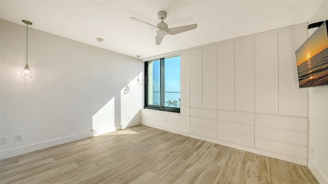 spare room with light wood-style floors, ceiling fan, and baseboards