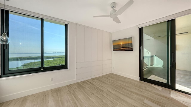 unfurnished room featuring light wood finished floors, a ceiling fan, and baseboards