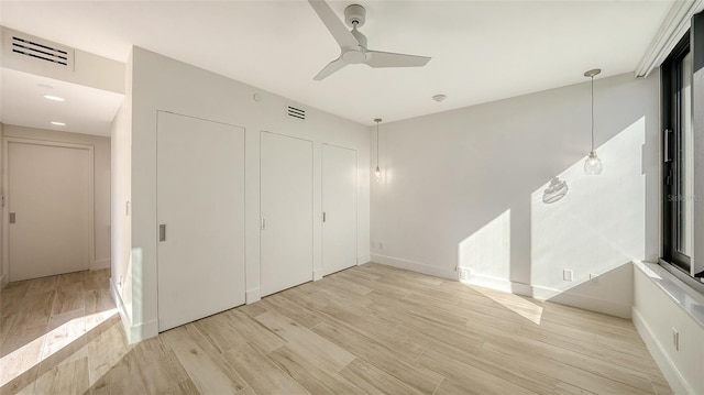 unfurnished bedroom with light wood-type flooring, baseboards, visible vents, and a ceiling fan