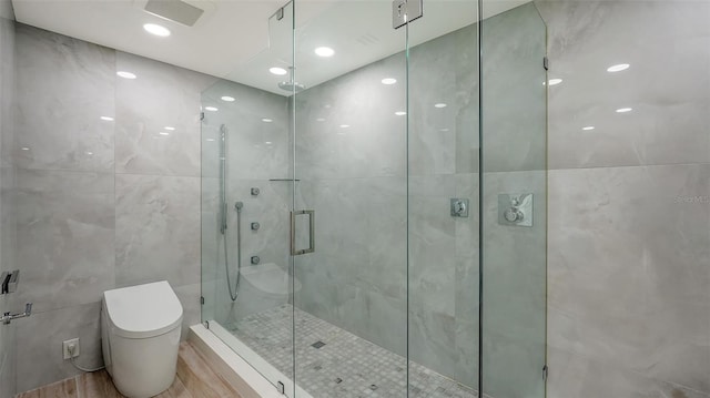 full bath with toilet, recessed lighting, wood finished floors, tile walls, and a stall shower