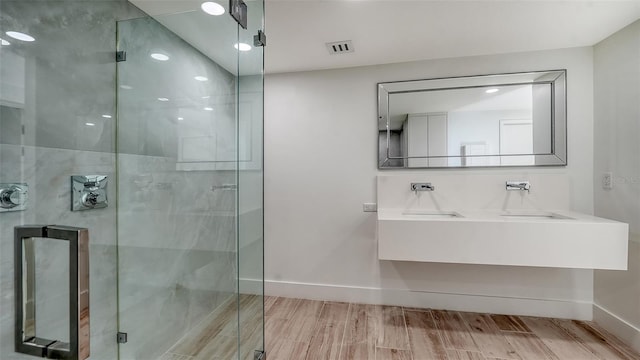 bathroom with a stall shower, wood finished floors, visible vents, and baseboards