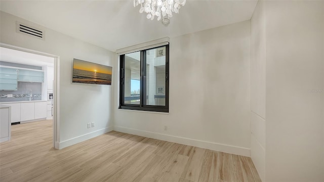 empty room featuring baseboards, visible vents, and light wood-style floors