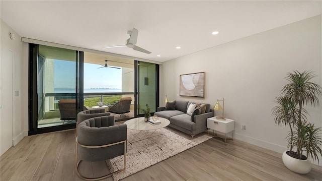 living room featuring light wood finished floors, baseboards, a ceiling fan, floor to ceiling windows, and recessed lighting