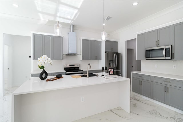 kitchen with hanging light fixtures, an island with sink, wall chimney exhaust hood, and appliances with stainless steel finishes