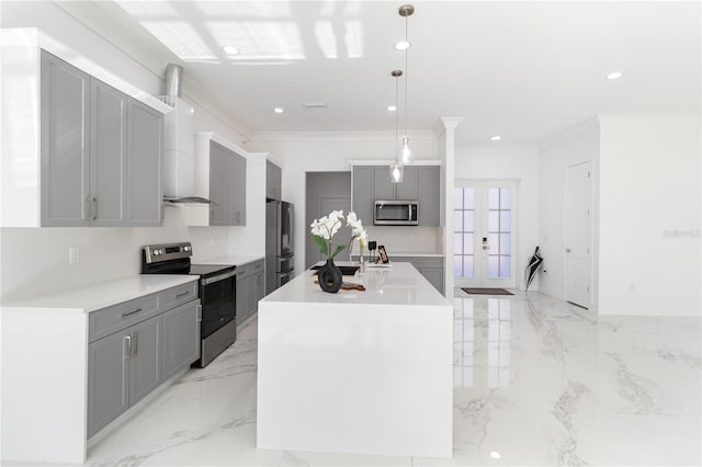 kitchen with appliances with stainless steel finishes, decorative light fixtures, gray cabinetry, a kitchen island with sink, and wall chimney range hood