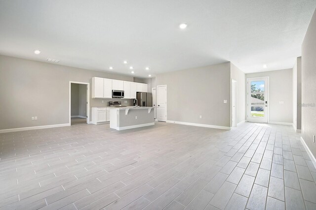 unfurnished living room featuring sink and light hardwood / wood-style floors