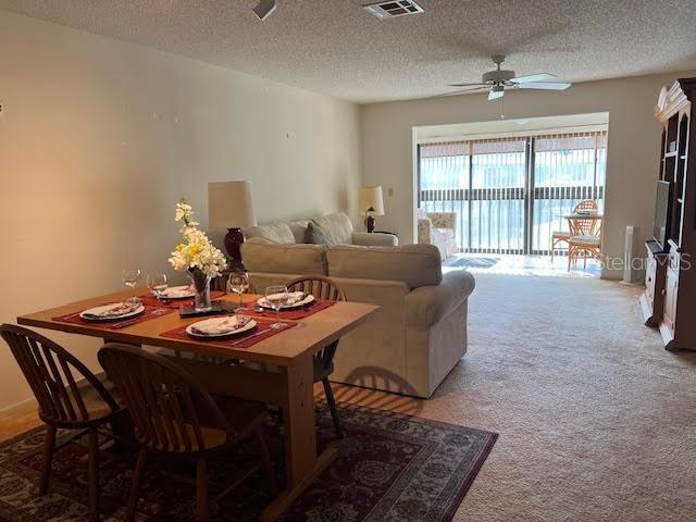 living room featuring ceiling fan, carpet, and a textured ceiling