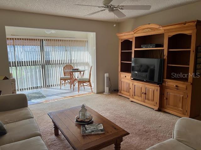 living room with ceiling fan, carpet, and a textured ceiling