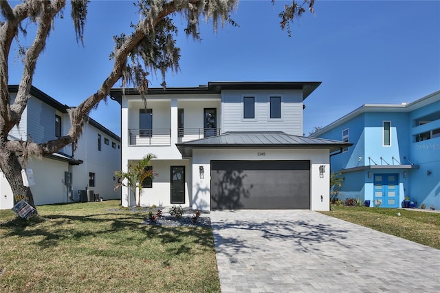 contemporary home with central AC unit, a garage, a front lawn, and a balcony