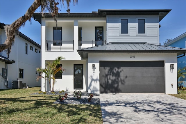 view of front of home featuring central AC, a balcony, a garage, and a front lawn