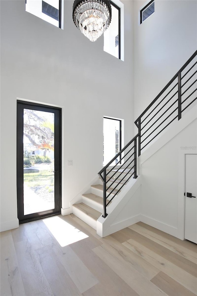 foyer entrance featuring a chandelier, a high ceiling, and light wood-type flooring