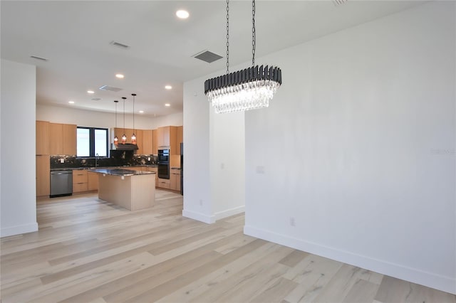 kitchen featuring an inviting chandelier, decorative light fixtures, stainless steel dishwasher, a kitchen island, and decorative backsplash