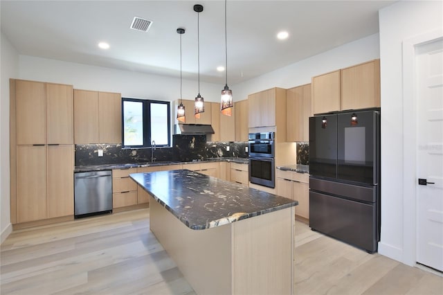 kitchen featuring decorative light fixtures, a center island, light brown cabinets, dark stone counters, and stainless steel appliances