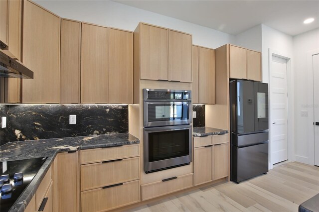 kitchen with dark stone countertops, tasteful backsplash, black appliances, and light brown cabinets