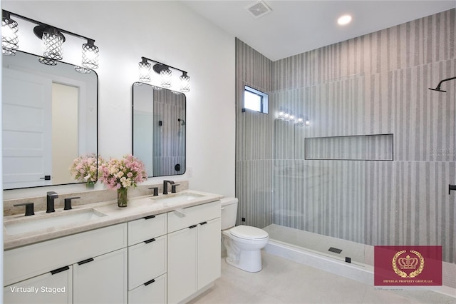 bathroom featuring vanity, tile patterned flooring, toilet, and tiled shower