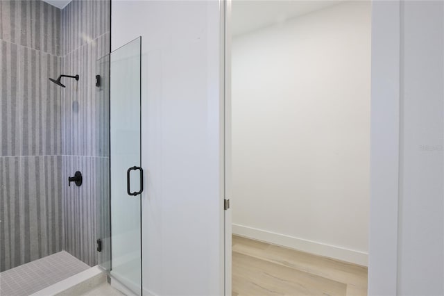 bathroom with wood-type flooring and a shower with door